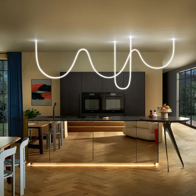 moderne Küche mit dunklen Schränken, Holzboden  und heller Beleuchtung